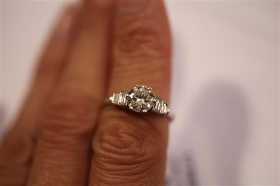 A platinum and single stone diamond ring with graduated emerald cut diamond set shoulders, size N.